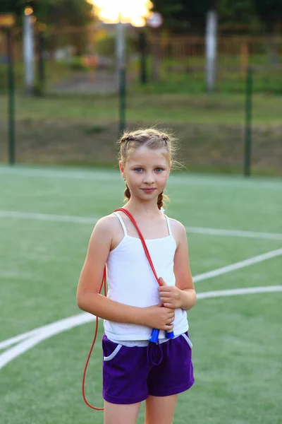 A menina senta-se no fio no chão de esportes — Fotografia de Stock