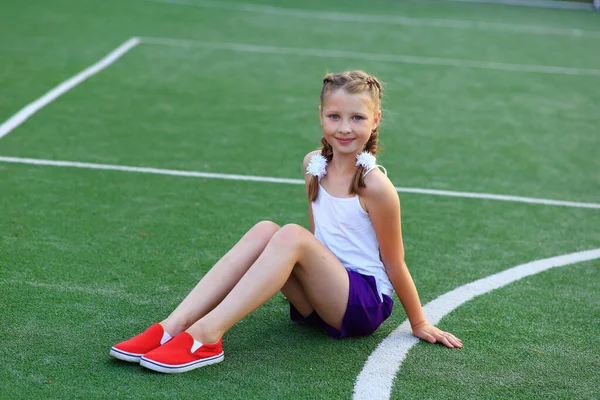 Девушка сидит на бечевке на спортивной площадке — стоковое фото