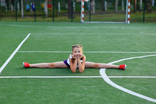 La chica se sienta en la cuerda en el campo de deportes —  Fotos de Stock