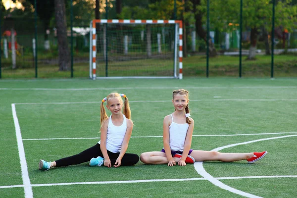 Dziewczyny siedzą na sznurku na boisku sportowym. — Zdjęcie stockowe