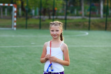 Kız spor sahasında sicimin üzerinde oturuyor.