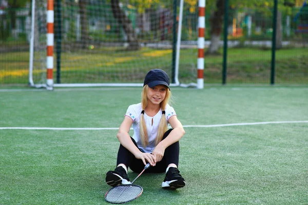 Meisje met een racket in haar handen op het sportveld. — Stockfoto