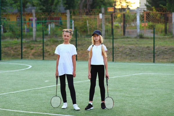 Dvě holky po vyučování jdou na tenis na hřišti. — Stock fotografie