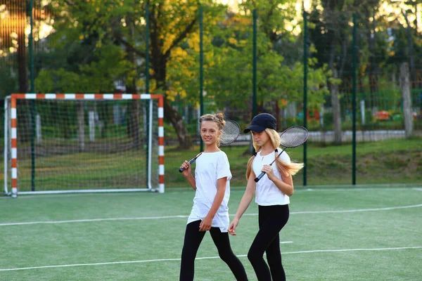 Dos chicas después de clases van a jugar al tenis en el patio de recreo. — Foto de Stock