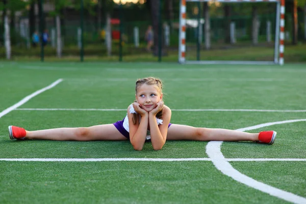 Das Mädchen sitzt am Bindfaden auf dem Sportplatz — Stockfoto