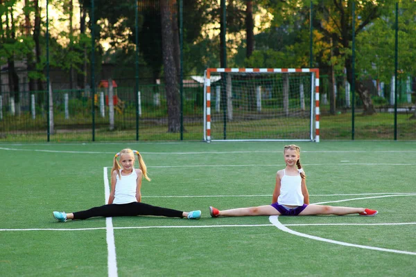 Les filles s'assoient sur une ficelle sur un terrain de sport. — Photo