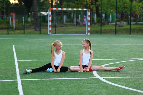 Meisjes zitten op een touw op een sportveld. — Stockfoto