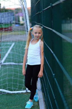 Spor sahasında futbol kalesine yakın poz veren bir kız..
