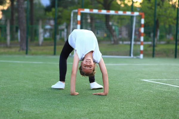 Menina está envolvida em ginástica no campo esportivo. — Fotografia de Stock