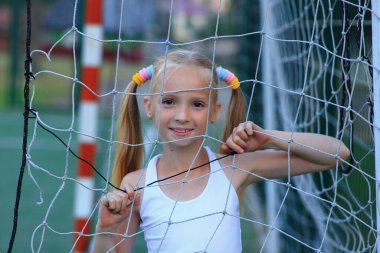 Spor sahasında futbol kalesine yakın poz veren bir kız..