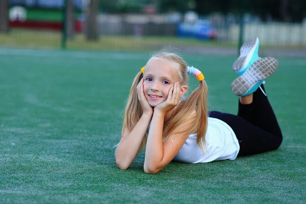 Una chica posando cerca de un gol de fútbol en un campo de deportes. — Foto de Stock