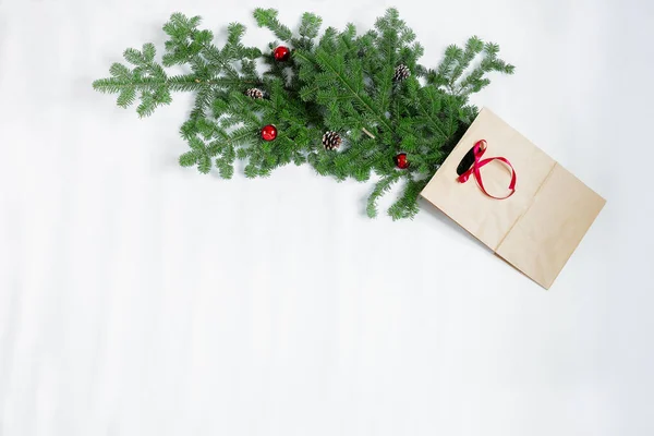 Ветки ели с новогодними игрушками и подарочный пакет лежат на белом фоне. — стоковое фото