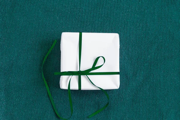 Gift in a white package on a green background. — Stock Photo, Image