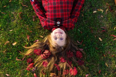 Saçında sonbahar yapraklarıyla yerde yatan güzel bir kız..