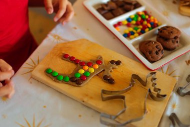 Noel Baba şapkalı bir çocuk mutfakta kurabiye hazırlıyor..