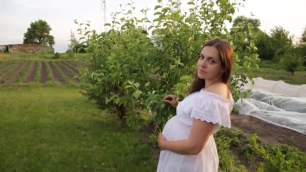 Una madre incinta sta camminando nel giardino vicino alla casa. — Video Stock