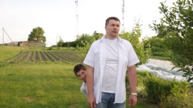 Baba ve oğul evin yakınındaki yeşil bahçede birlikte yürüyorlar..