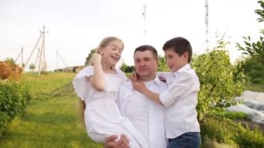 Baba ve iki çocuk evin yakınındaki yeşil bahçede birlikte yürüyorlar..