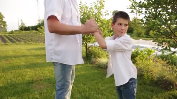 Papá e hijo caminan juntos en el jardín verde cerca de la casa. — Vídeo de stock