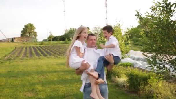 Papà e due bambini camminano insieme nel giardino verde vicino alla casa. — Video Stock