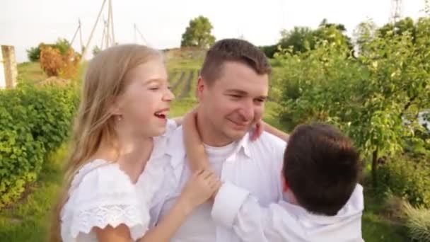 Papa et deux enfants marchent ensemble dans le jardin verdoyant près de la maison. — Video