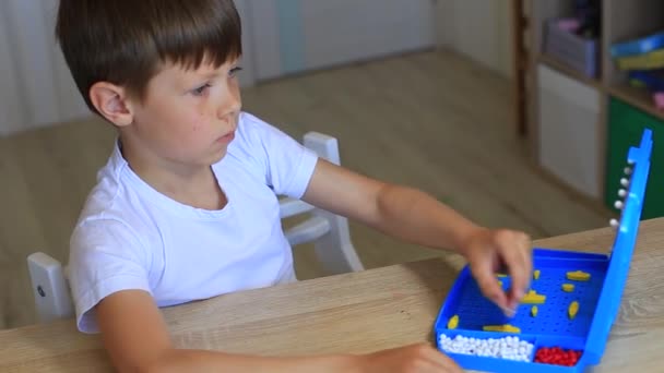 En pojke spelar ett brädspel hemma. — Stockvideo