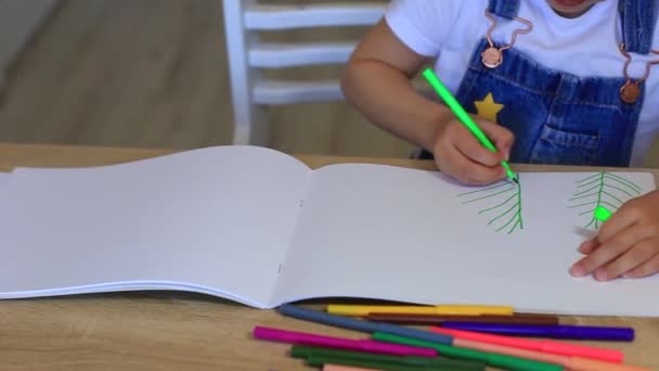 L'enfant dessine sur du papier avec des crayons de couleur à l'isolation de la maison. — Video