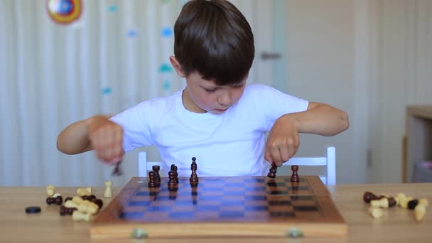 Ett barn spelar schack. Barn i isolering lär sig på distans ett parti schack. — Stockvideo