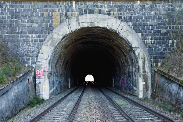 Railway tunnel on double track. Railway infrastructure. Light at the end of the tunnel. Old stone tunnel painted with graffity.