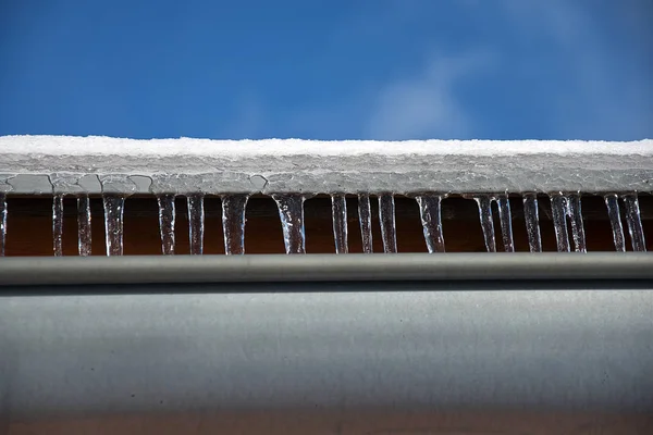Dach z rynny deszczowej zimą. Dach z śniegiem i sople. — Zdjęcie stockowe
