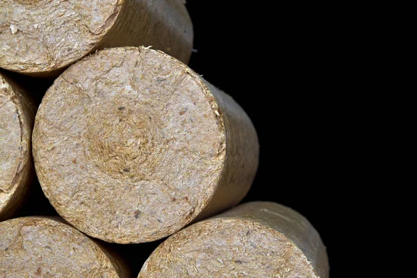 Wood sawdust briquettes straightened, black background. Alternative fuel, bio fuel — Stock Photo, Image