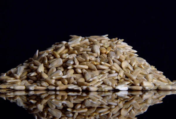 Sunflower peeled seeds on a black glass background — Stock Photo, Image