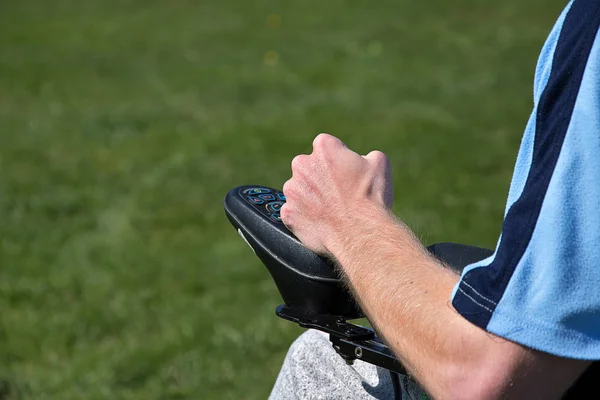 Electric wheelchair. Young man controls a wheelchair with his left hand.