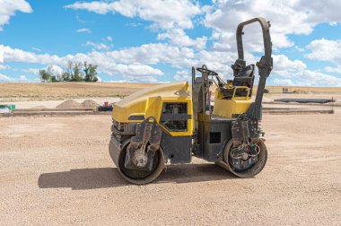 İnşaat alanında küçük bir buharlı silindir, zemini düzleştiriyor.