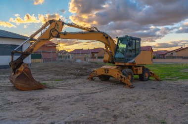 Günün sonunda bir inşaat sahasında kazıcı.