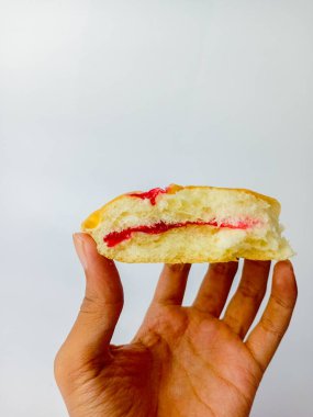 Beyaz arka planda yaban mersini reçelli yarım ekmek tutarken,.