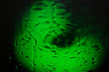 Soyut çizim. Su ile bulanık yeşil spot karanlık bir arka plan üzerinde damla.