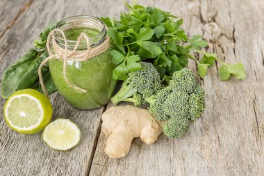 Smoothies yeşil sebze ve çevresinde çeşitli yeşil sebzeler üzerinde eski bir ahşap arka plan kırık. Vitaminler vücut detoks temizlik, kokteyl.