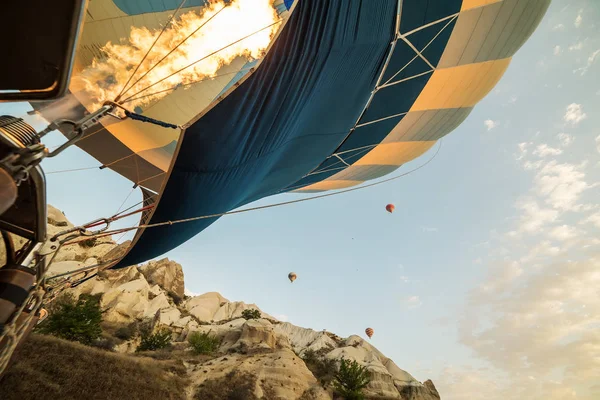 Flight in a hot air balloon. Inflating the balloon with gas, fire and a huge ball against the backdrop of the rocky mountains in the early morning.