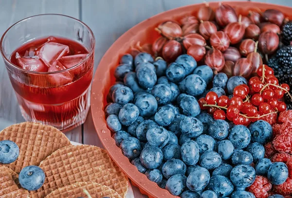 Different berries and wafers with cheese and a fruit cold drink.