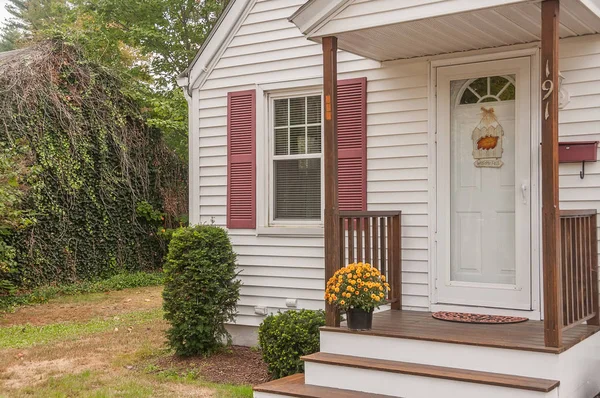 The porch of a small cozy wooden house and with yellow chrysanthemums on the threshold. USA. Maine. Home simple comfort.