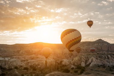 Balonların şafak taşlara arka planı. Şafak güneş ışığı altında büyük renkli topları. Türkiye. Cappadocia. Göreme Milli Parkı.