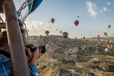 Sepete bırakılan bir piçsin bir balon hava balonu uçan uçuş içinde fotoğraf çekimi bir adam. Fantastik alan ve balonlar. Türkiye. Cappadocia. Göreme Milli Parkı.