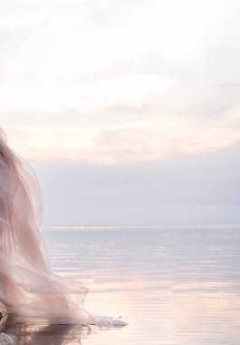 Gün batımında suda yumuşak şeffaf kumaş. Su ayarı bulutlarda pembe yansıması.