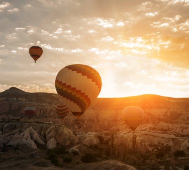 Balonların şafak taşlara arka planı. Şafak güneş ışığı altında büyük renkli topları. Türkiye. Cappadocia. Göreme Milli Parkı.