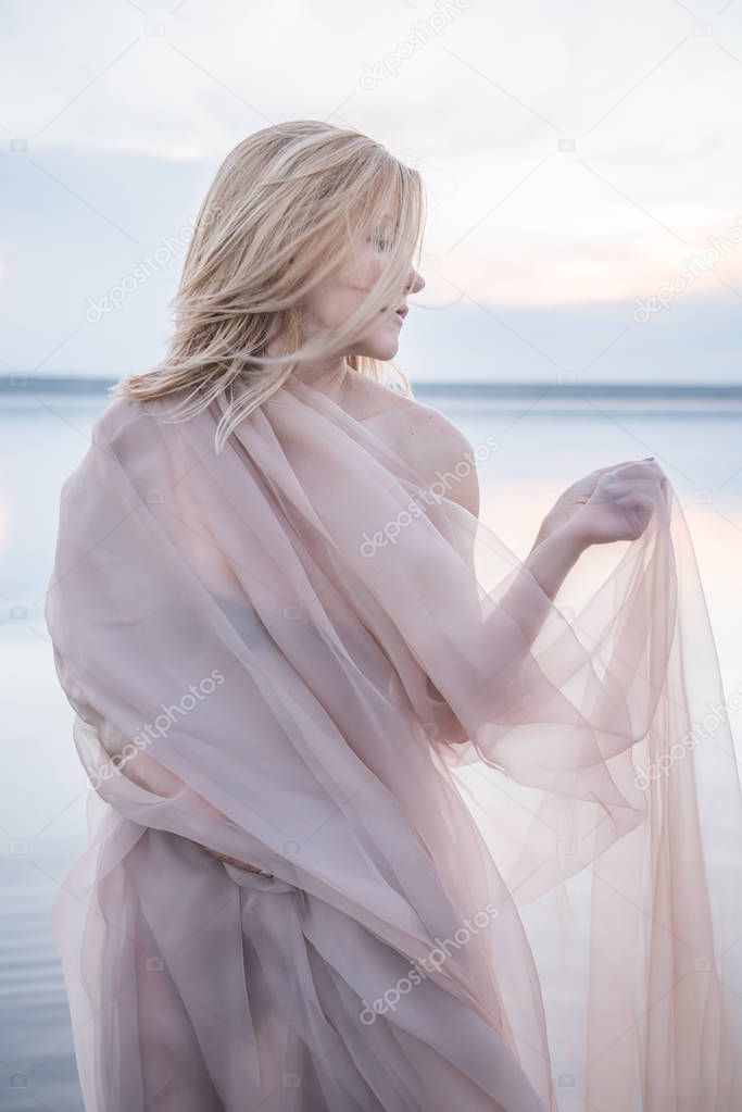 Fantastic girl in a light fabric on a lake in the water.
