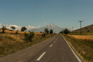 Ufuk ve karlı bir tepe ile dağ giden yol.