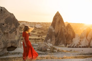 Sivri kaya zemin karşı güneş ışığı altında kırmızı elbiseli bir kız. çok hafif sanatsal fotoğraf. Cappadocia. Türkiye.
