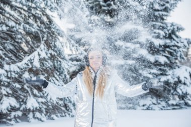 Güzel bir kız bir orman glade büyük ağaçlar arasında üzerinde kar atar.