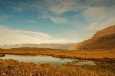 İzlanda manzara. Alanları, dağlar arka plan üzerinde küçük bir göl expanses.